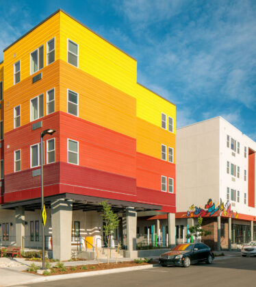 Four story apartment building complex with brightly colored siding