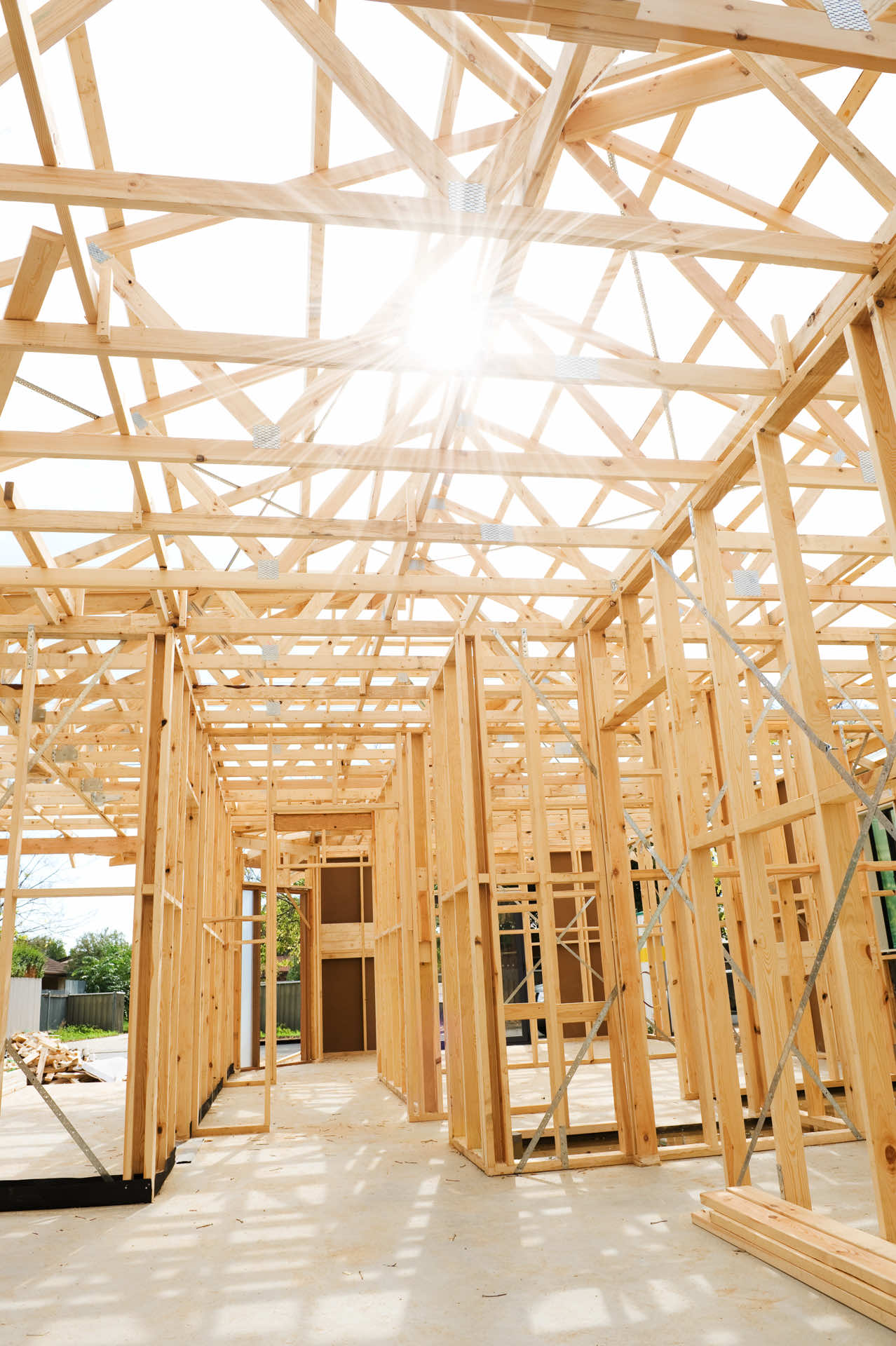 House framing under construction with sunlight shining through roof