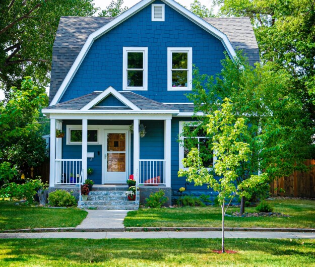 Small blue house with trees and green grass